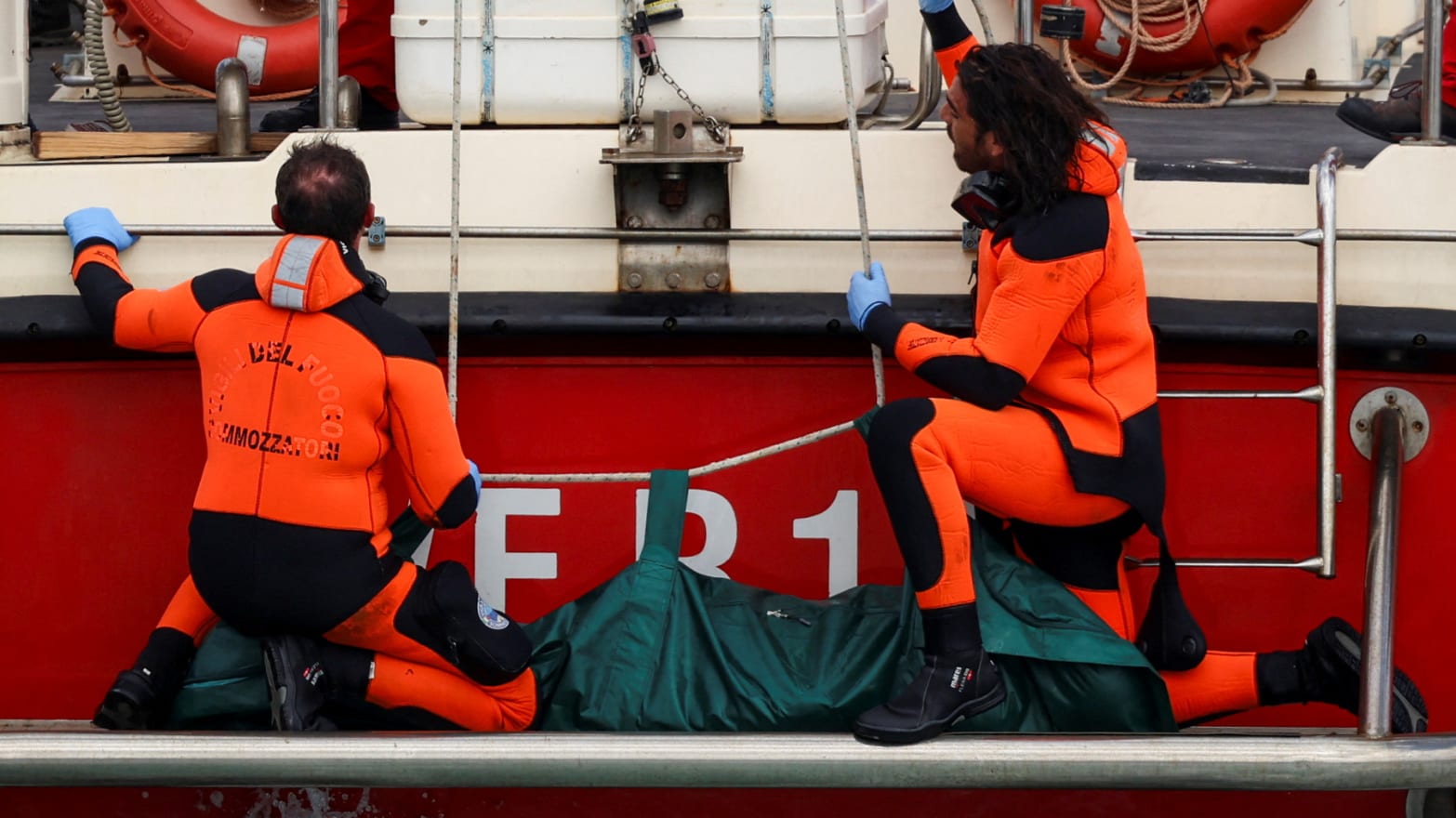 Divers board a ship with a body bag.