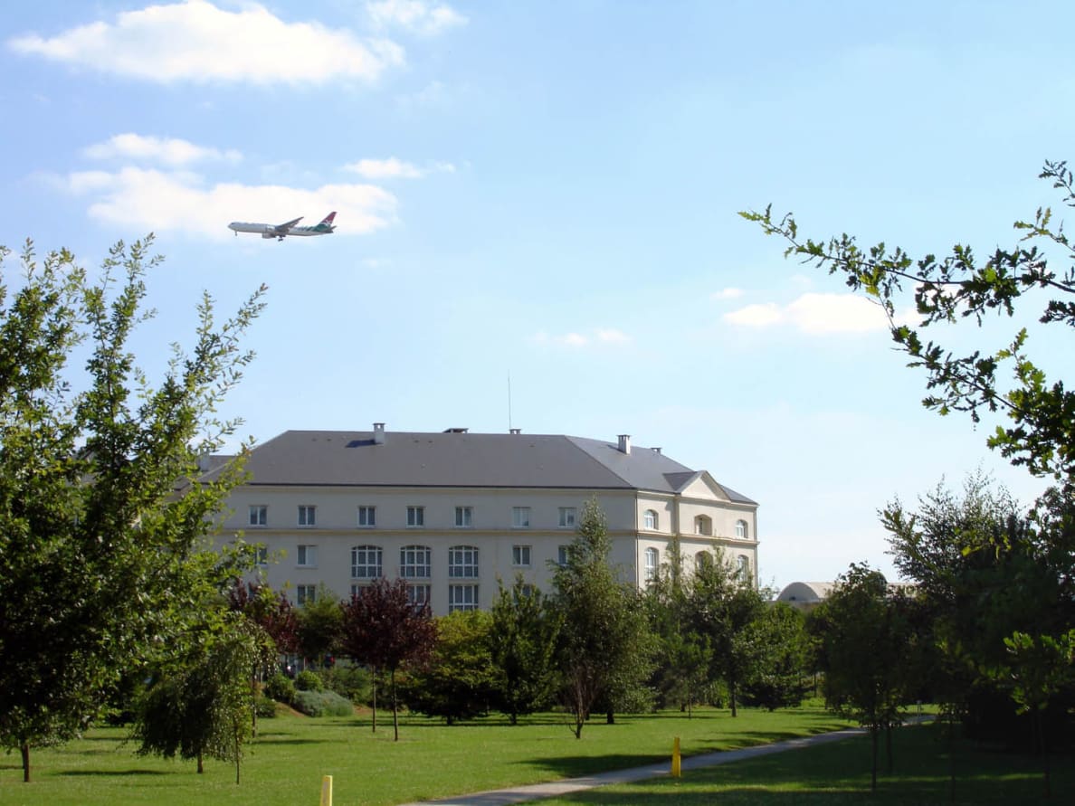 A photograph of an airplane flies over the hotel zone in Roissy-en-France.