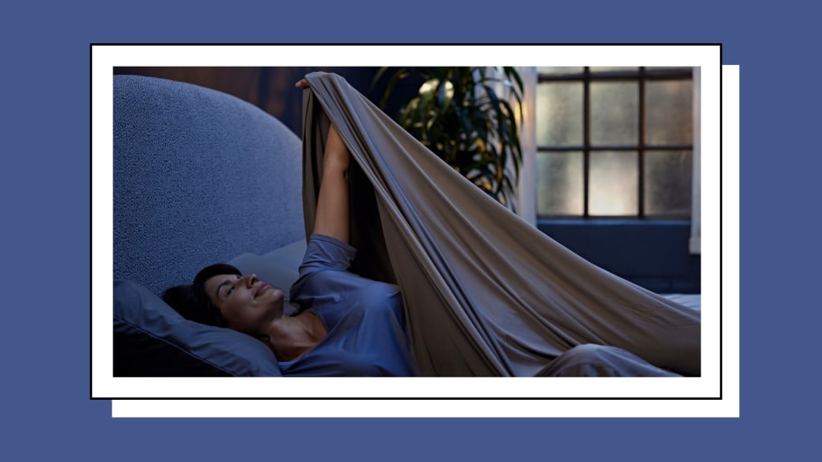 Woman sleeping in a large bed with grey sheets.