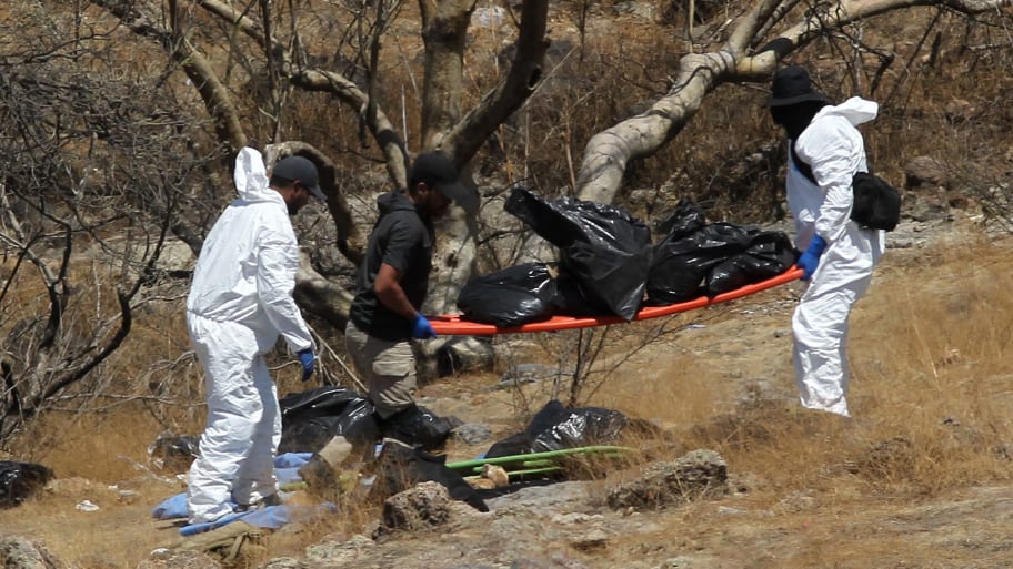 Forensic experts work with several bags of human remains extracted from the bottom of a ravine by a helicopter, which were abandoned at the Mirador Escondido community in Zapopan, Jalisco state, Mexico on May 31, 2023.