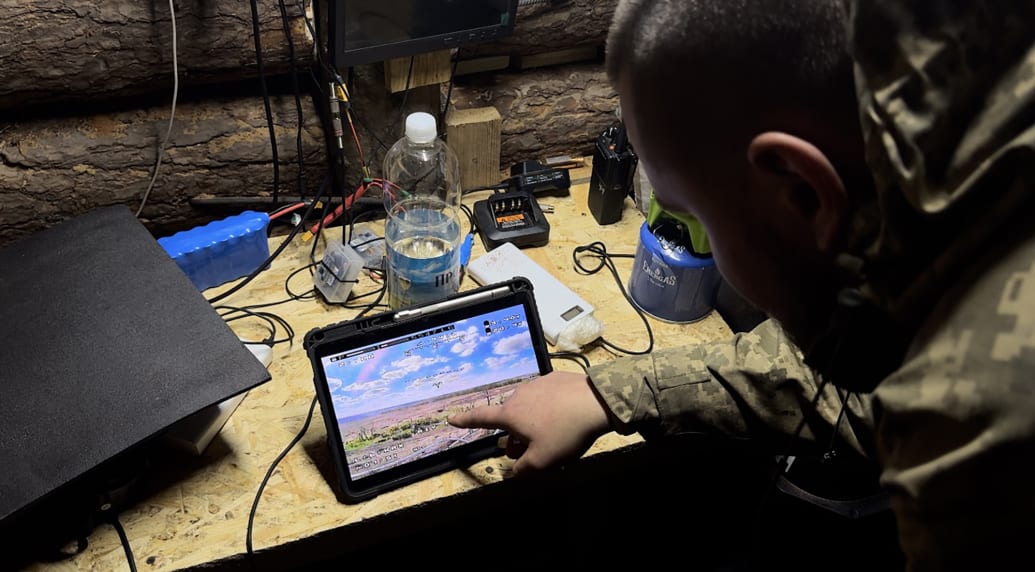 A Ukrainian soldier operating a drone from a trench.