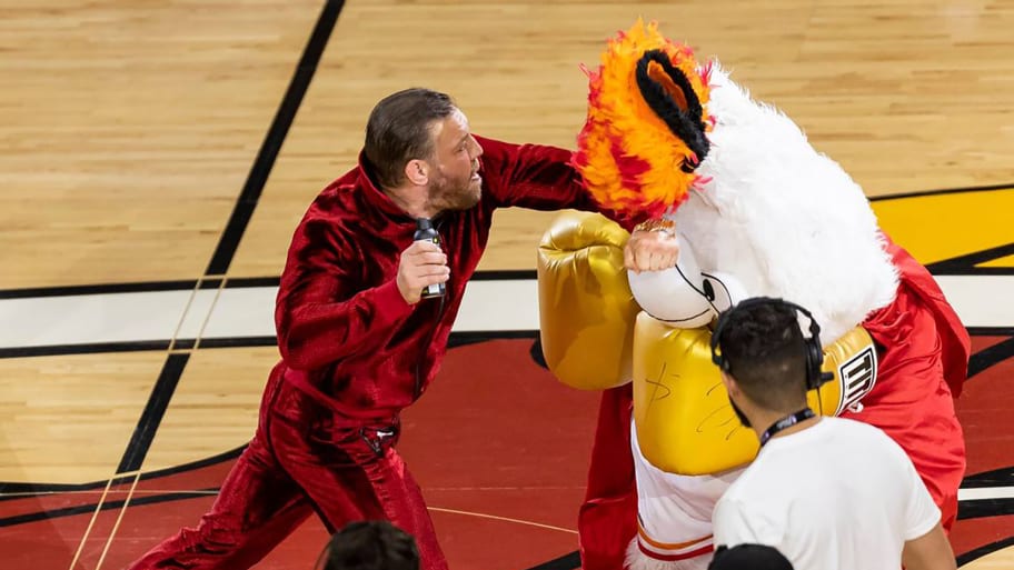 Conor McGregor, left, swings at Miami Heat mascot Burnie