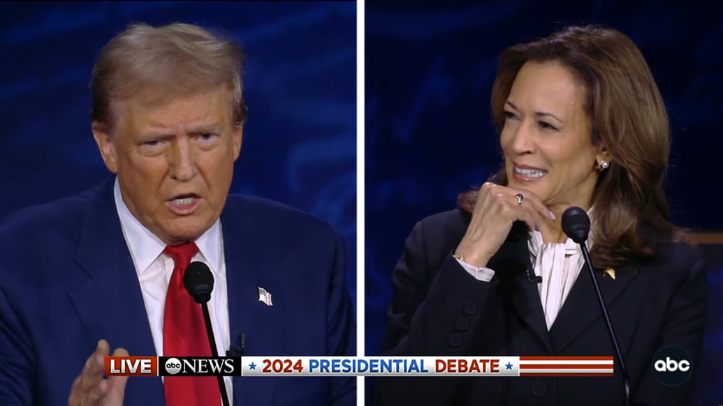 Kamala Harris with her chin in her hand watching Donald Trump in a TV split screen during their debate