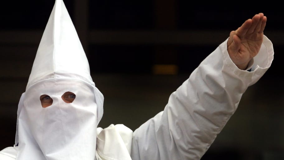 A Klansman raises his left arm during a chant at a Ku Klux Klan rally