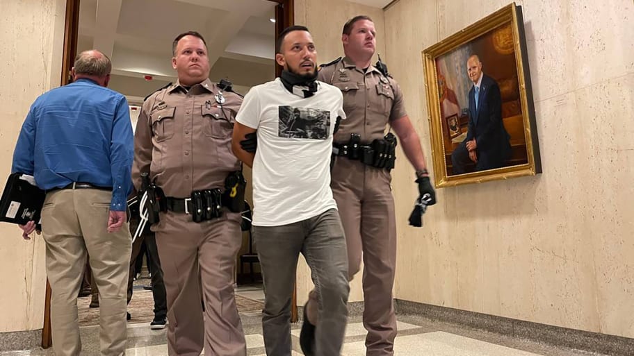 An unidentified protester is arrested and escorted out of Gov. Ron DeSantis’ office suite.