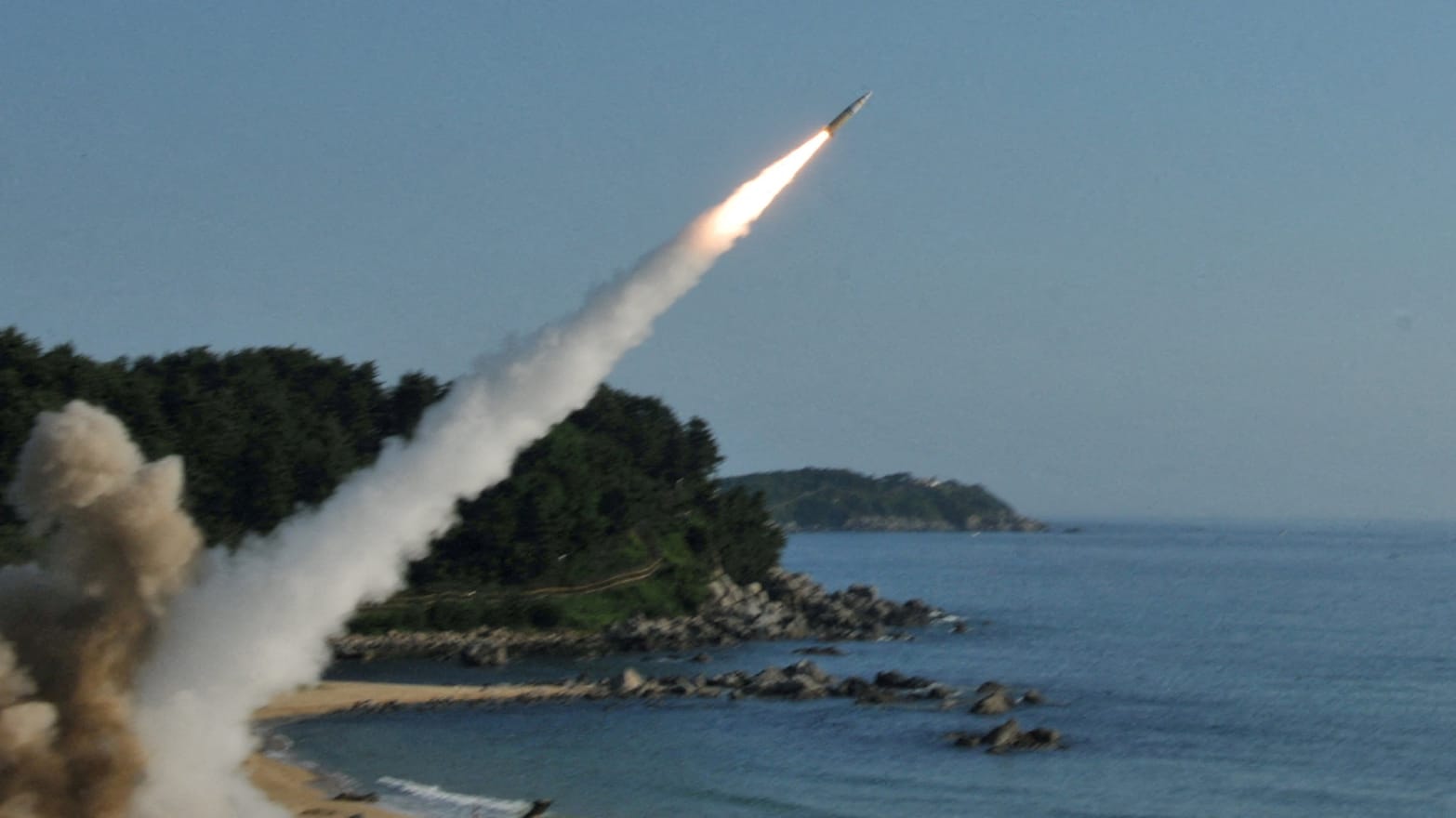 A missile launching over a shoreline.