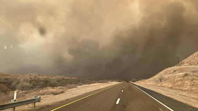 Smoke rises on the roadway in Hutchinson County after the Juliet Pass fire broke out in Armstrong County, Texas.