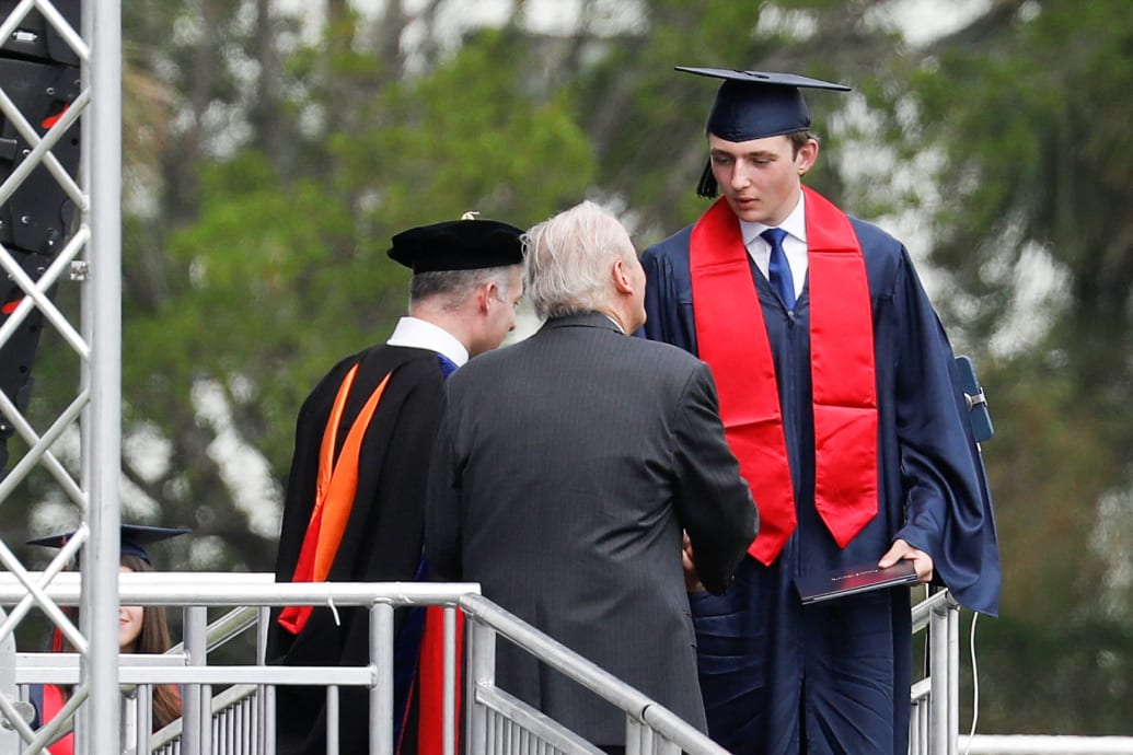 Barron Trump in mortar board and gown shaking hands when he graduates.