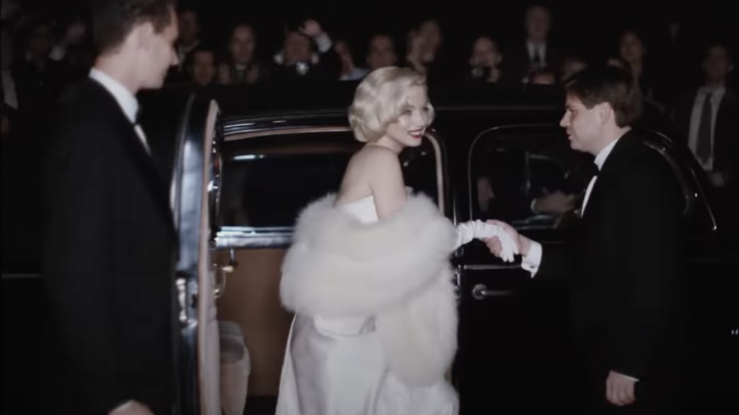 A woman in a fur coat is helped out of a limousine. 
