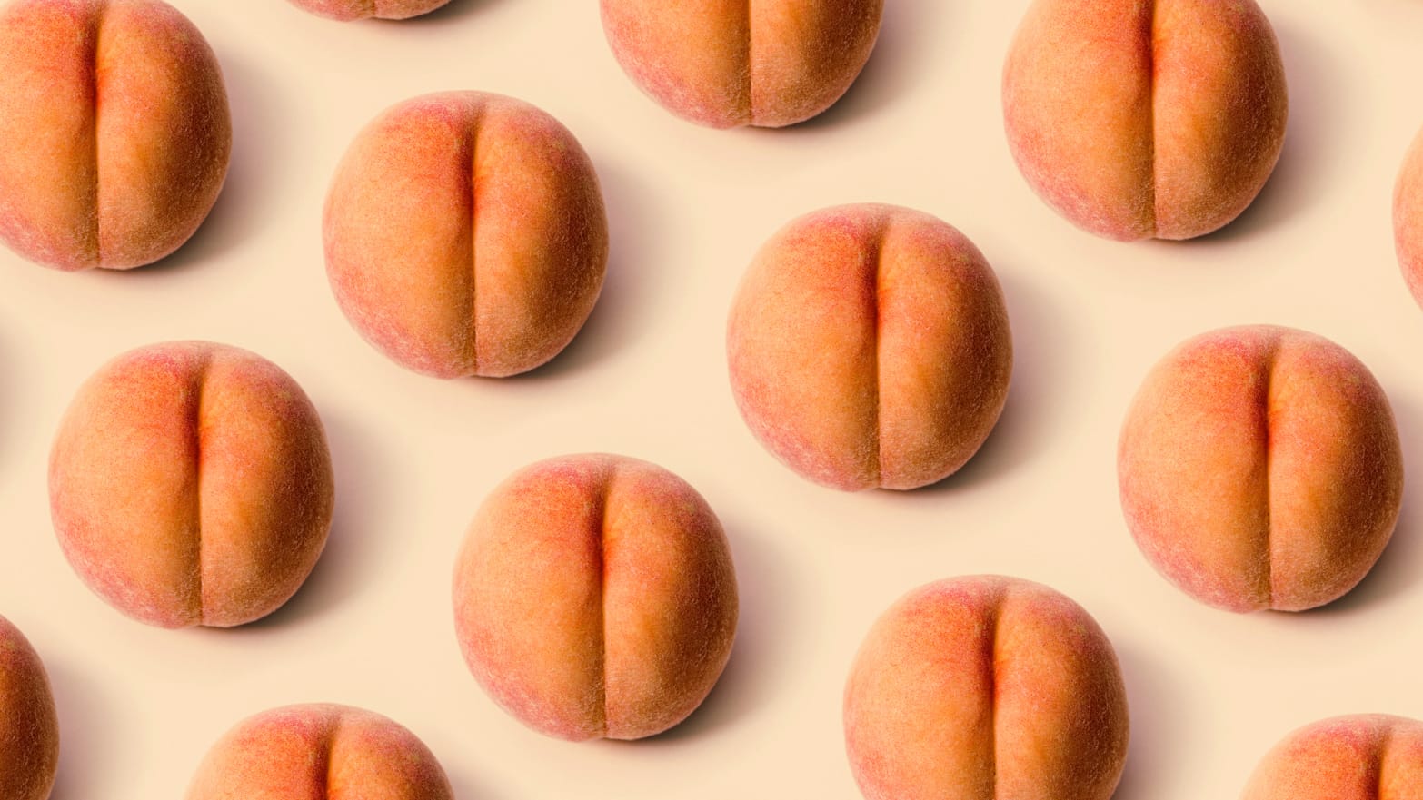 A photo of rows of peaches against a peach-colored background.