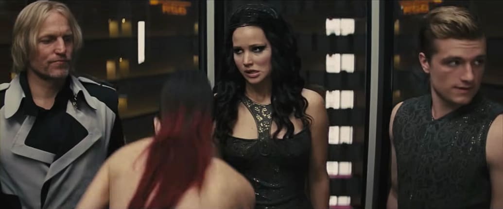 A still from The Hunger Games Catching Fire scene of Jena Malone in the elevator naked with Harrelson, Lawrence, Hutcherson shocked by her.