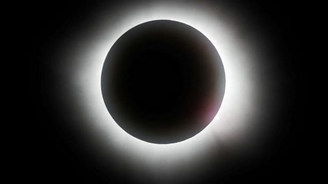 The sun slips behind the moon in a total solar eclipse.