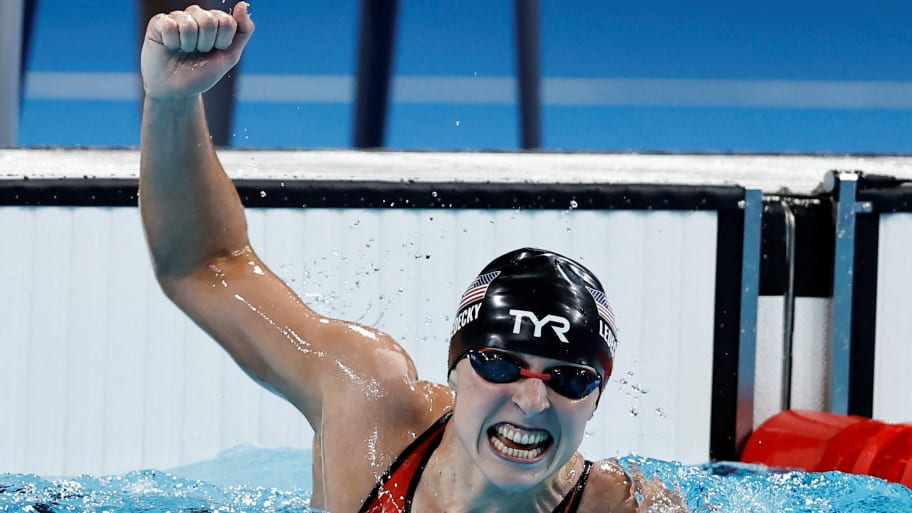 Katie Ledecky raises a fist from inside the pool after winning gold.