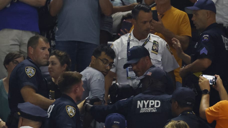 NYPD officers remove one of three climate change protesters during the U.S. Open. Sayak Mukhopadhyay, 50, has now been charged with criminal trespass and disorderly conduct and Gregory Schwedock, 35, has been charged with criminal trespass.