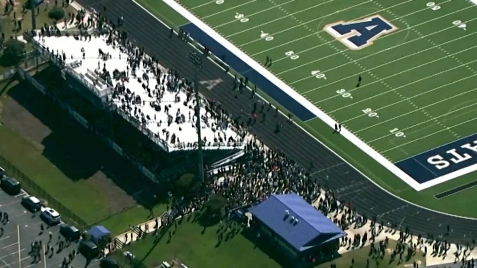 Students and staff gather next to the football field after law enforcement officers responded to a fatal shooting at Apalachee High School.