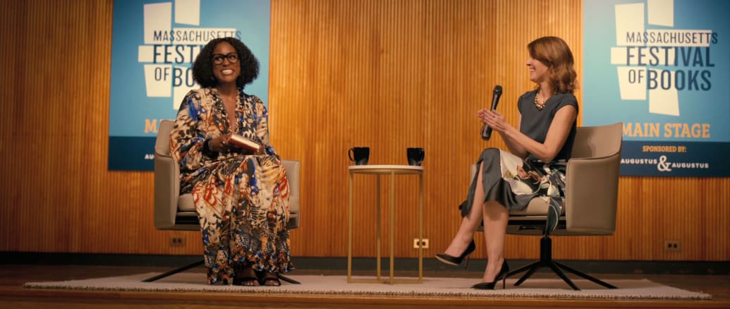 A picture of Issa Rae sitting on stage with a moderator at a book reading in a still from ‘American Fiction’