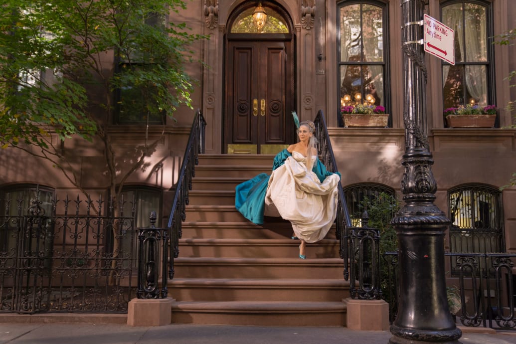 A still of Carrie Bradshaw standing outside the front of her Upper East Side apartment in And Just Like That.