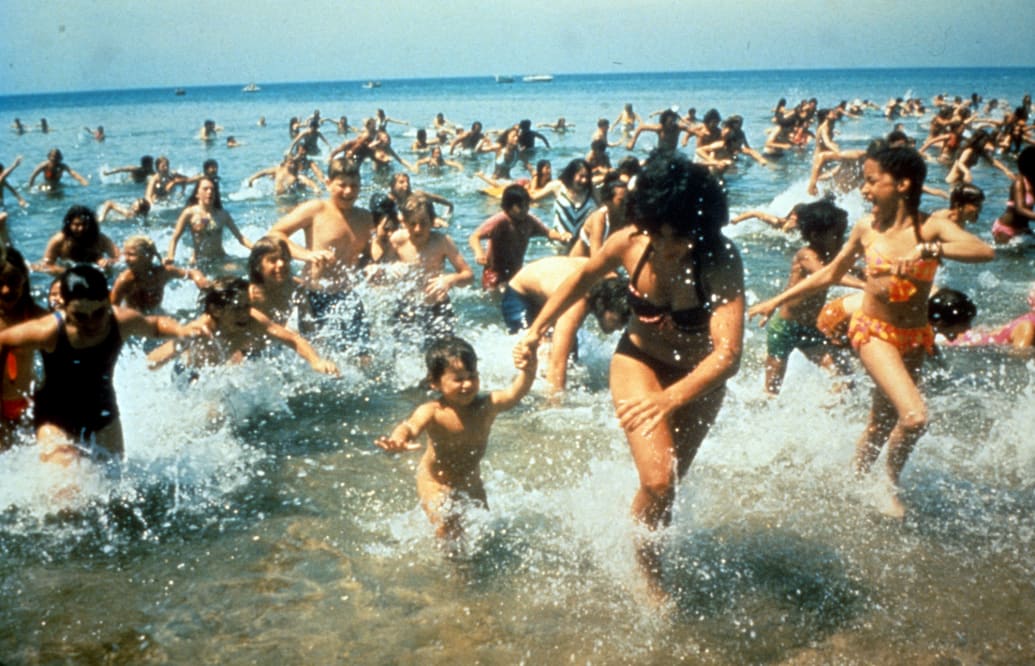 Crowds of people run out of the water in a beach scene from the film 'Jaws' in 1975.