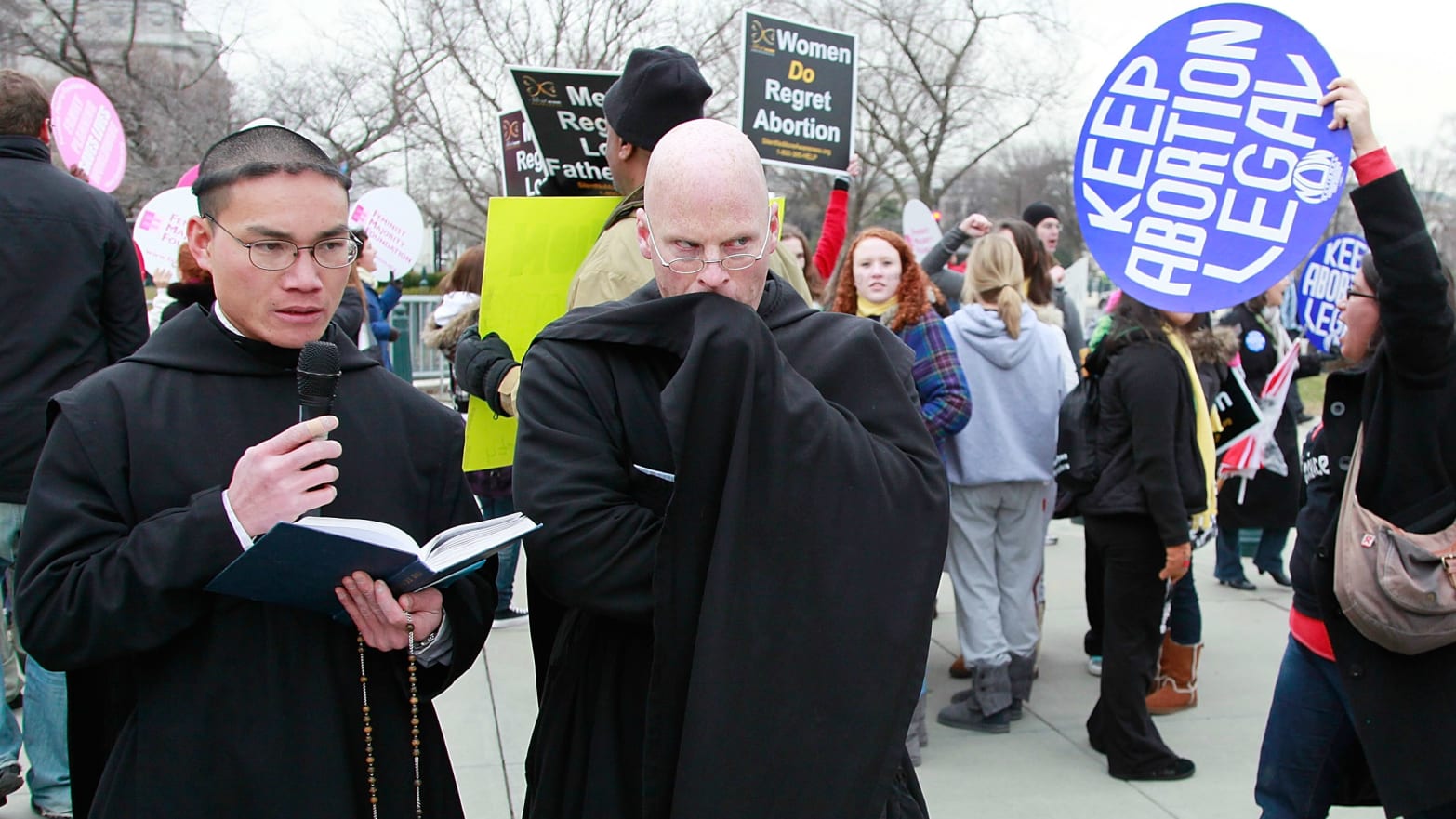 Father Gabriel (L) and Brother Bernard (2nd-L) of Our Lady of Guadalupe Monastery in New Mexico, participate in a prayer while Pro-choice advocates protest nearby.