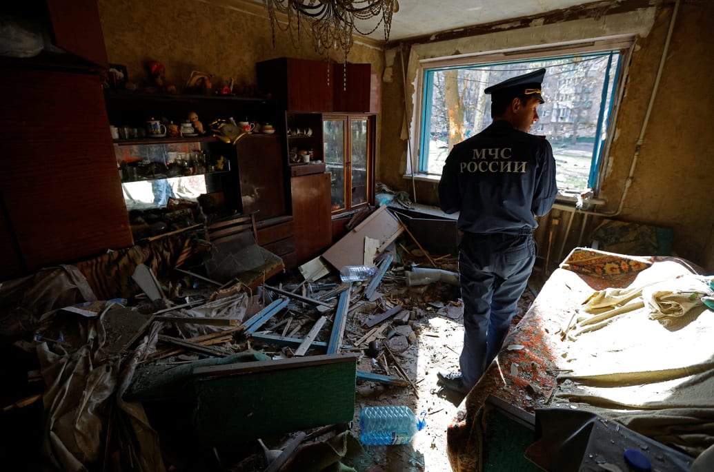 A member of Russia's emergencies ministry inspects a damaged flat inside an apartment.
