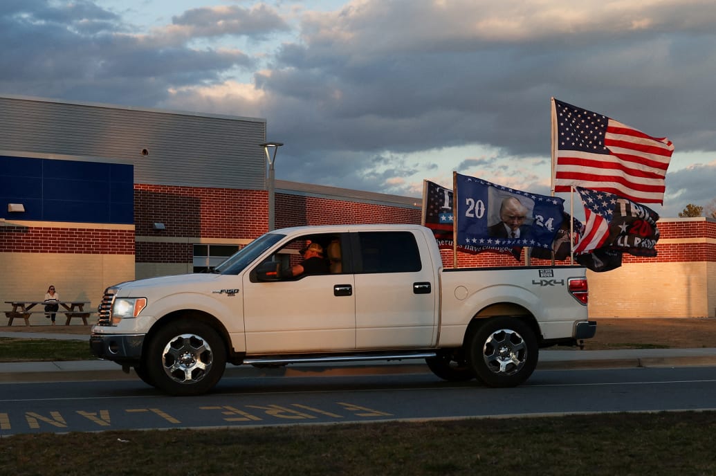 A supporter of former President Donald Trump drives a car outside a Nikki Haley event.