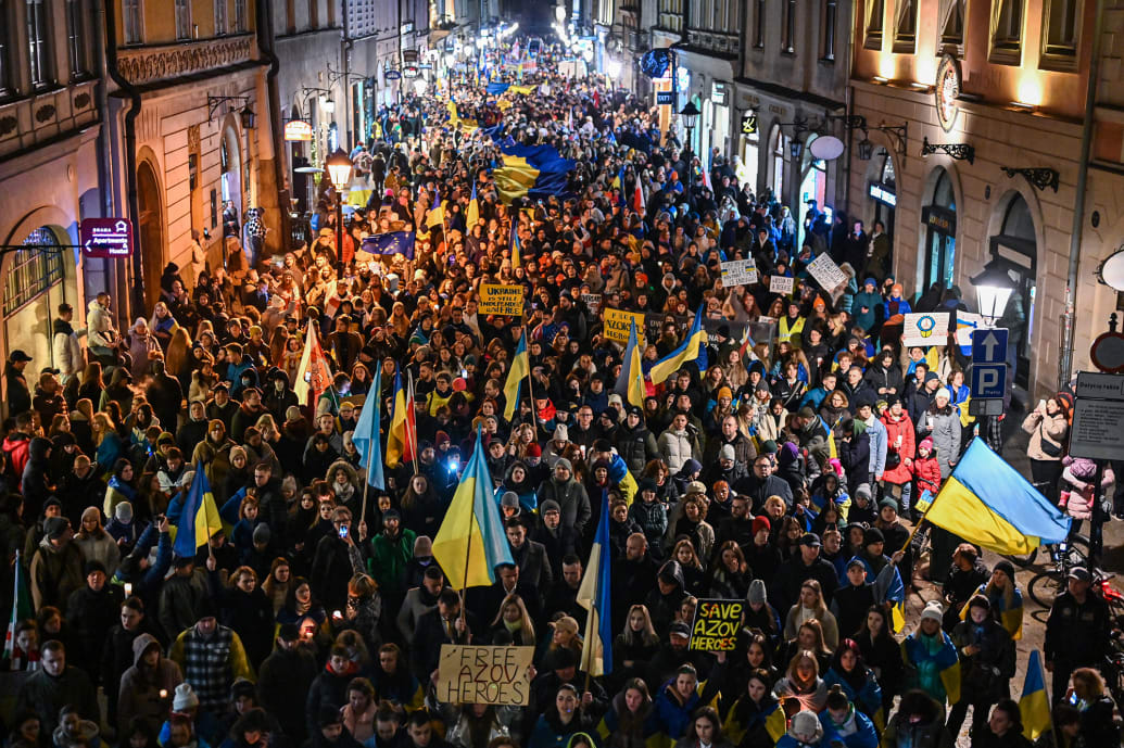 A photo of people holding banners and Ukrainian flags as they take part in a March for Victory as they move from Krakow’s Main Square.