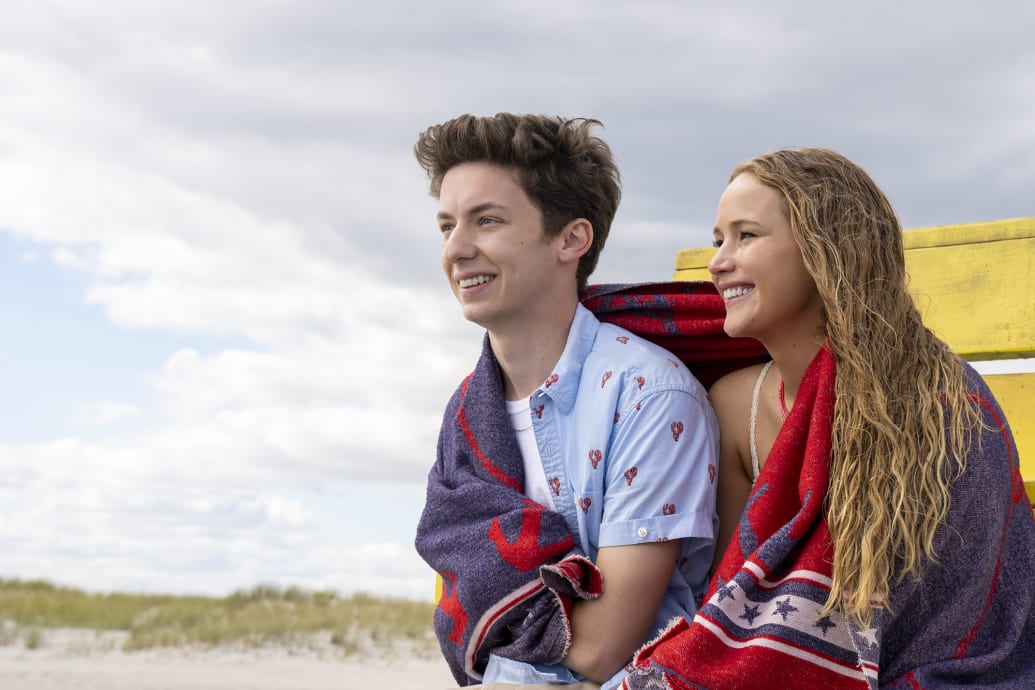Jennifer Lawrence y Andrew Feldman se sientan en la playa durante una escena de la película No Hard Feelings.