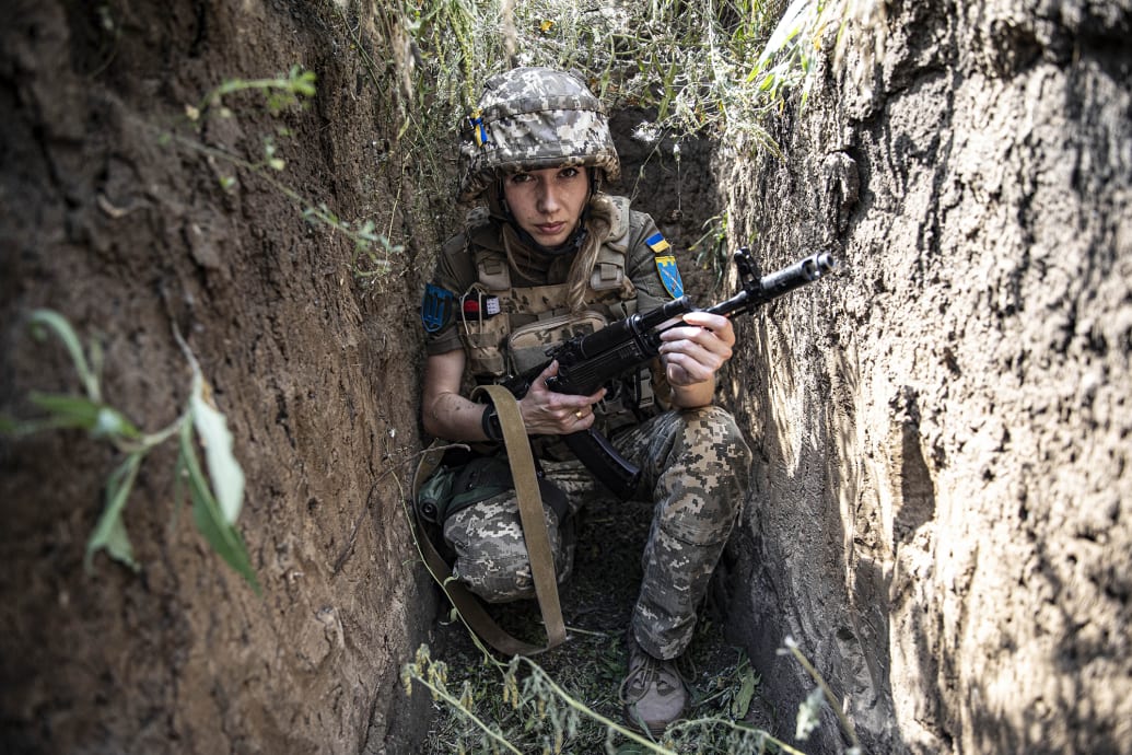 A photo of a Ukrainian soldier sitting in a trench with a rifle in 2022.