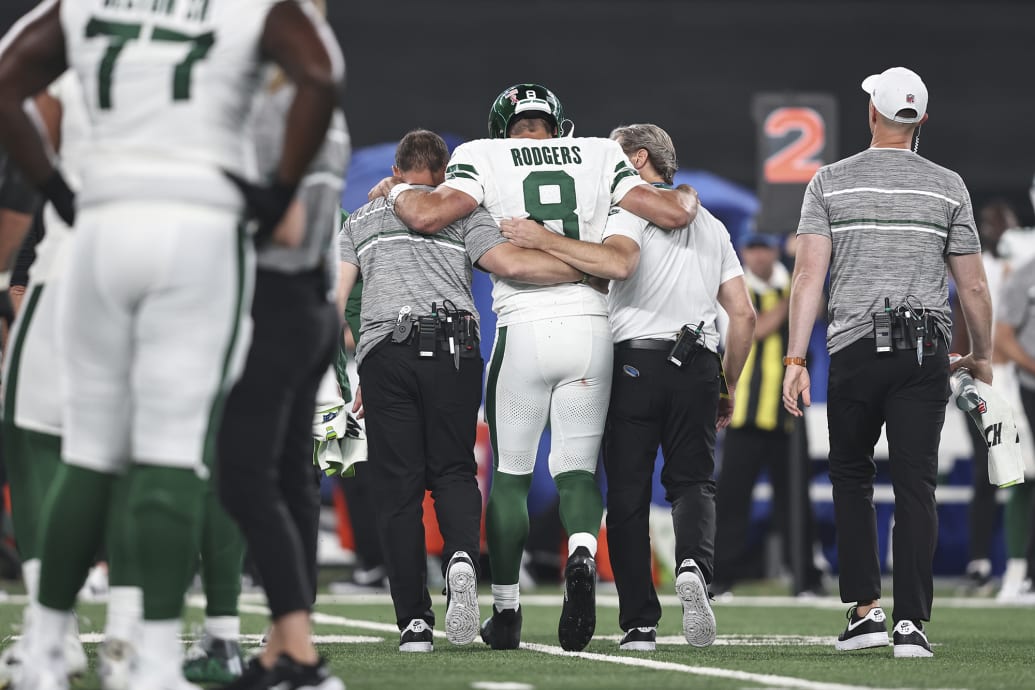 Aaron Rodgers of the New York Jets is helped off the field for an apparent injury.