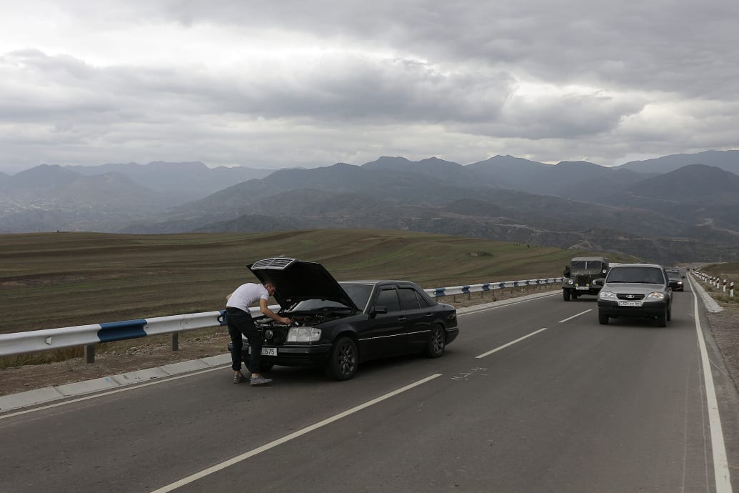 A person works on a broken down car as Armenians flee Nagorno-Karabakh.