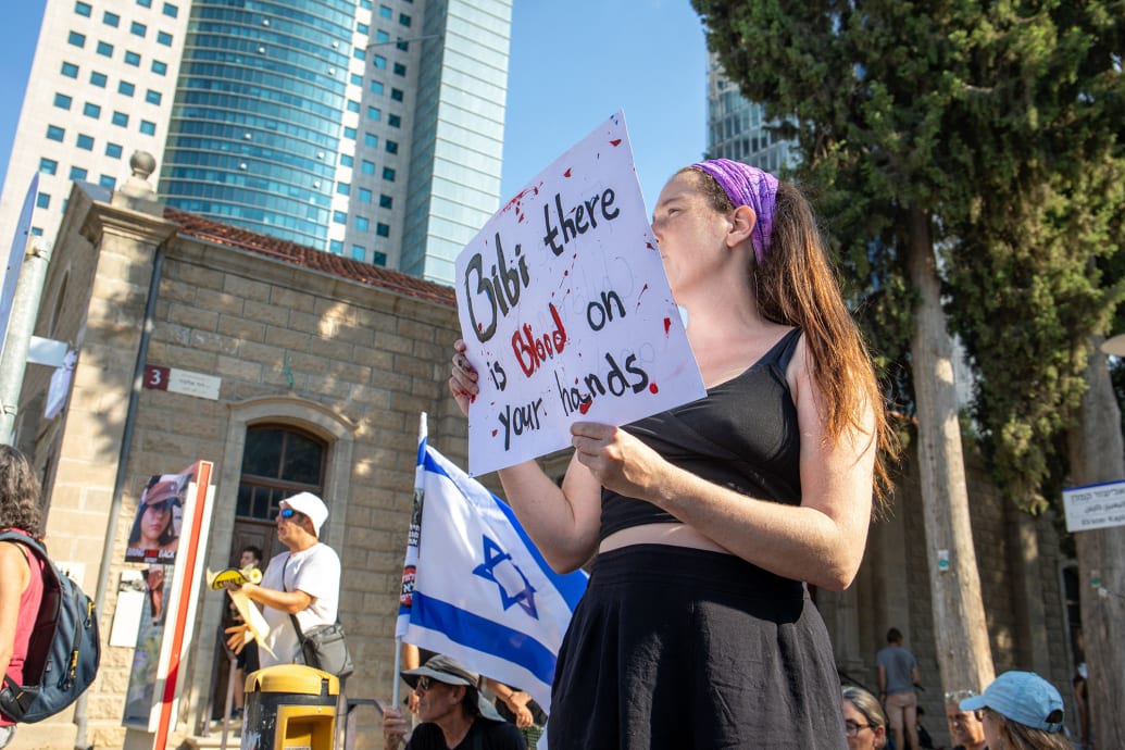 A protester holds a sign saying "Bibi, you have blood on your hands"