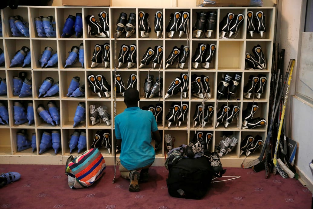 A member of Kenya's ice hockey team looks for skates before a practice session.