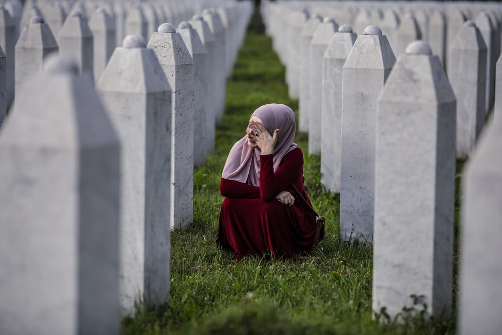 A Bosnian Muslim woman cries between graves of her father, two grandfathers and other close relatives, all victims of Srebrenica genocide.
