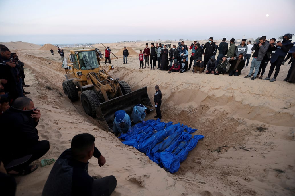 Palestinians bury people killed by Israeli strikes, after their bodies were released by Israel, at a mass grave in Rafah, Gaza.