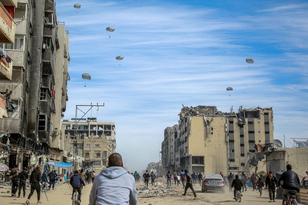 Palestinians run along a street as humanitarian aid is airdropped in Gaza City.