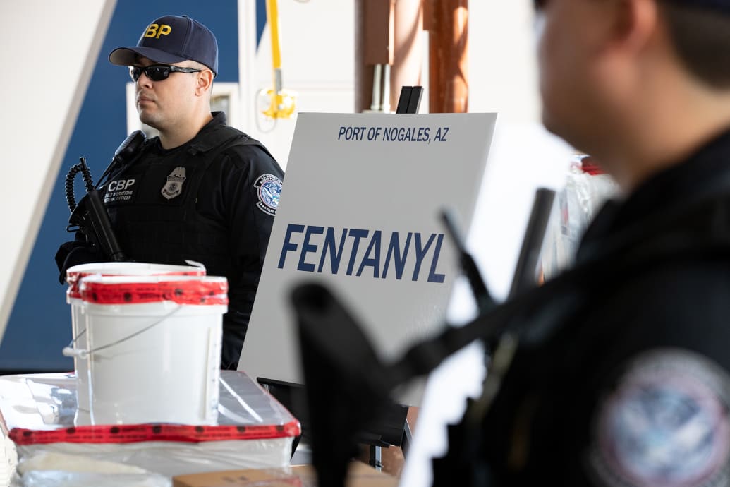 CBP agents stand near a seizure of fentanyl and methamphetamine.