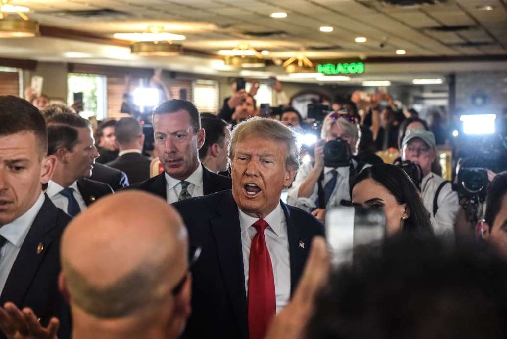 A photo of former President Donald Trump greeting people in a restaurant in Miami, Florida, after being arraigned in court.