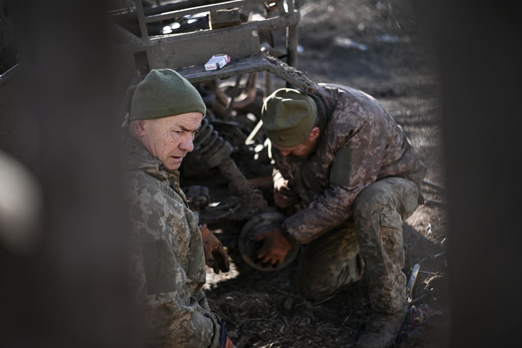 Soldiers try to repair the broken-down dune buggy in Ukraine.