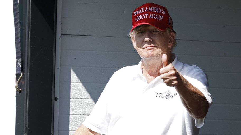 Former President Donald Trump gestures to fans from a hospitality suite on the eighteenth green during the first round of the LIV Golf DC 2023 tournament at Trump National Golf Club in Sterling, Va.