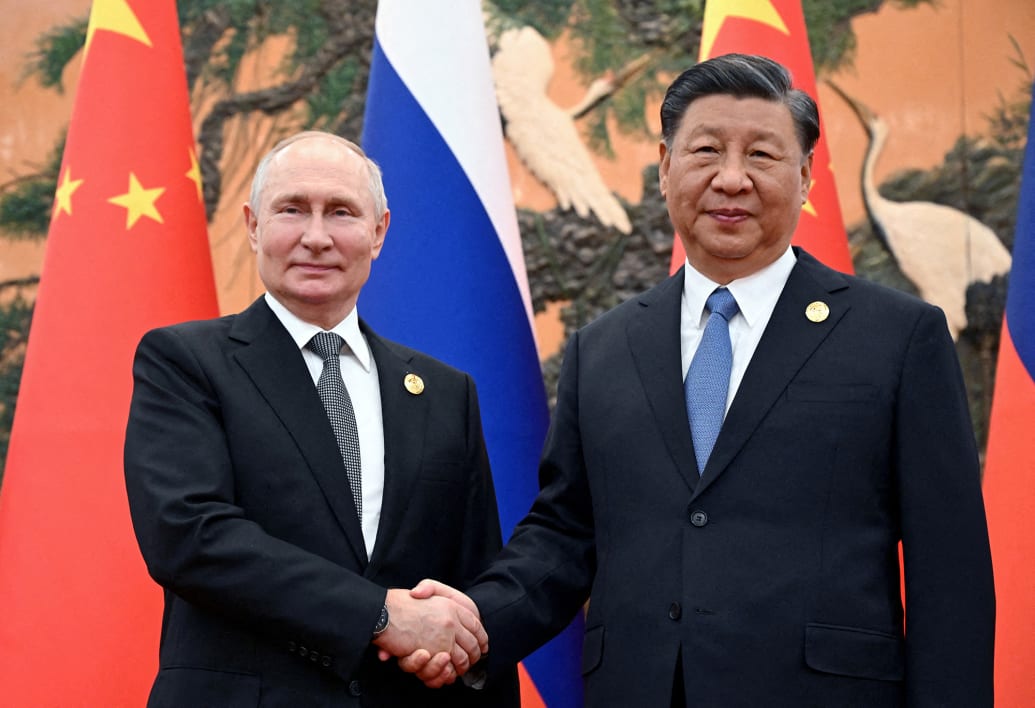 Russian President Vladimir Putin shakes hands with Chinese President Xi Jinping.