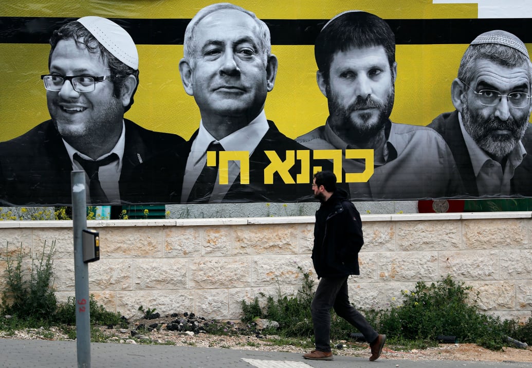 An Israeli man walks past an electoral billboard bearing portraits of Prime Minister Benjamin Netanyahu.