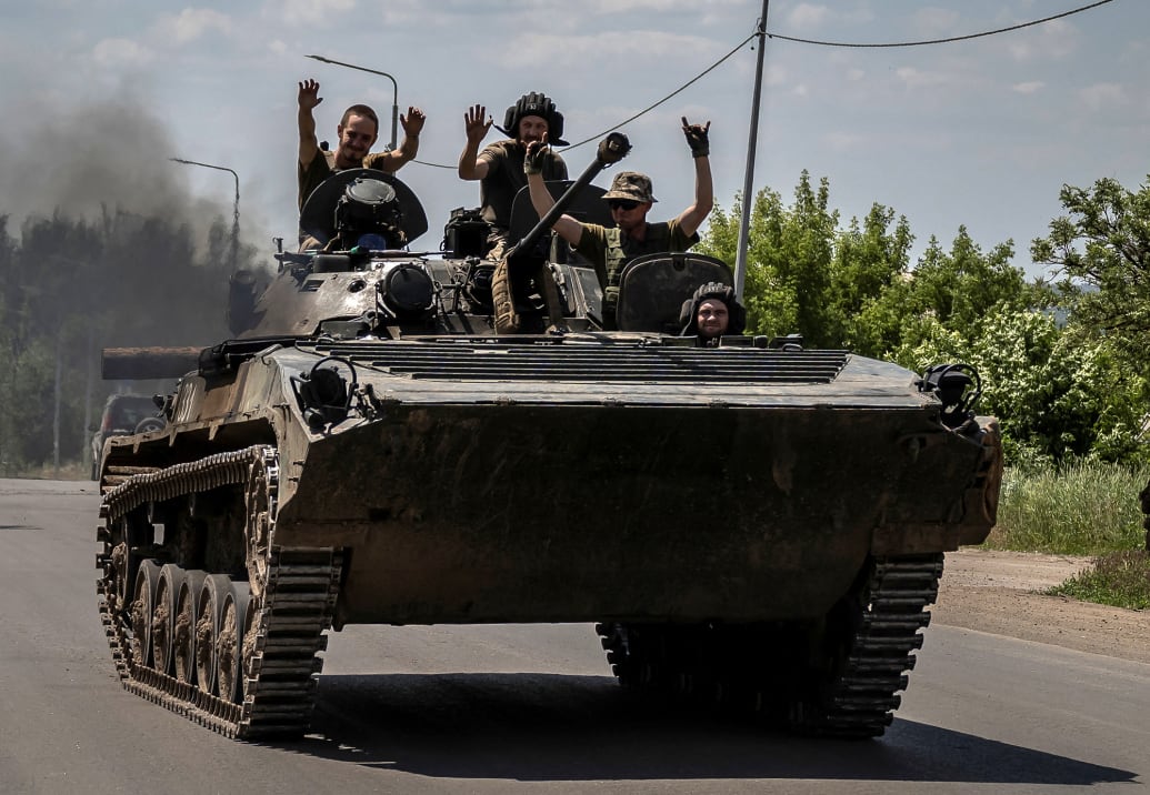 Ukraine soldiers ride on top of an armored vehicle during the war against Russia.