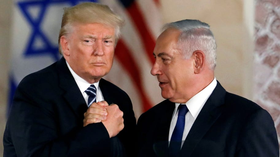 Donald Trump and Benjamin Netanyahu clasp hands together.
