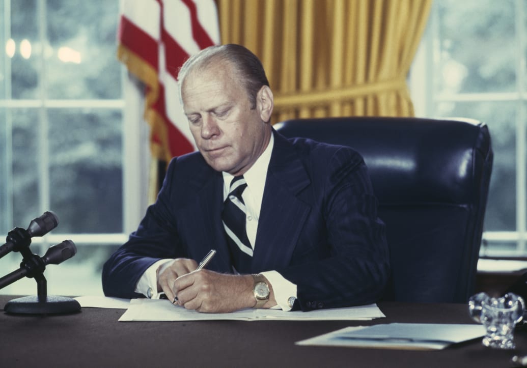 President Gerald Ford signs a document granting former President Richard Nixon a full pardon.