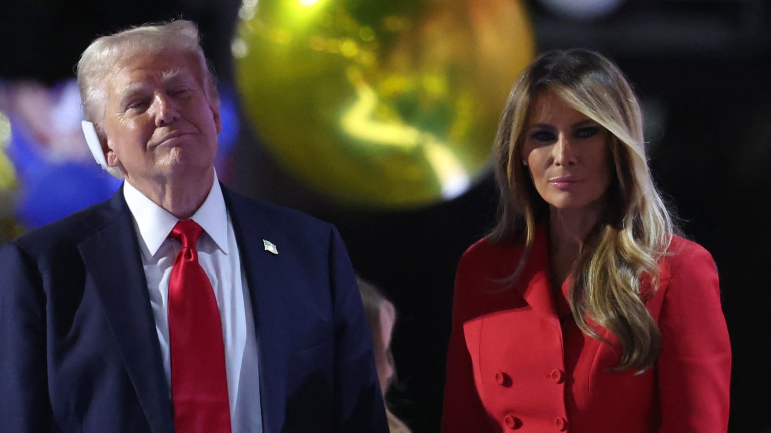 Donald and Melania Trump in front of a gold balloon