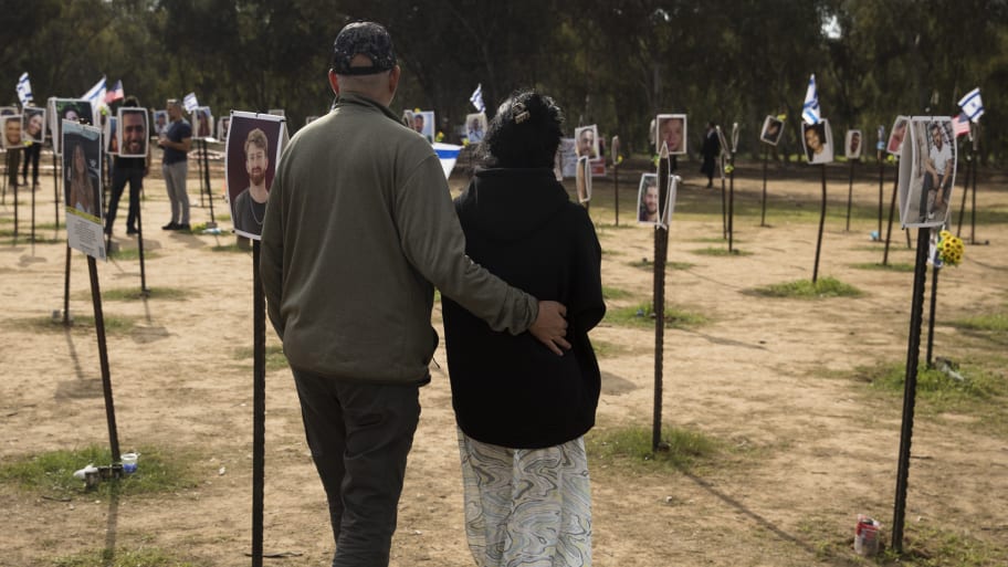 People walk past photos of victims at the Nova music festival site on January 5, 2024 in Re'im, Israel