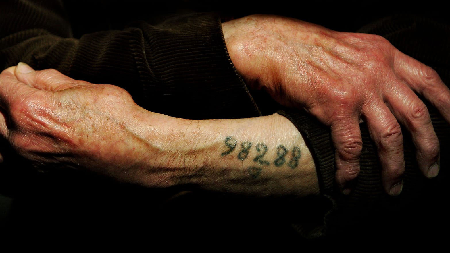 Auschwitz survivor Mr. Leon Greenman, prison number 98288, displays his number tattoo.