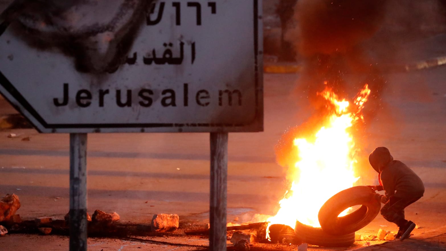 A Palestinian protester sets up a burning barricade near the West Bank city of Ramallah December 8, 2017.