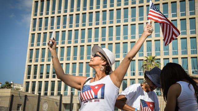 A tourist makes a selfie holding a US Flag in front of the US Embassy in Havana