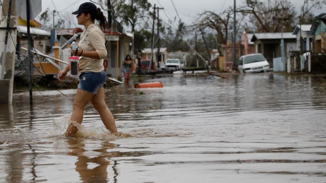 A woman wades through a flooded street after the area was hit by Hurricane Maria in Salinas, Puerto Rico, September 21, 2017.